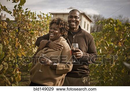 Stock Photo - Black couple drinking wine in vineyard. Fotosearch