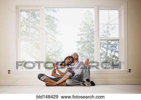 Stock Photo - Black couple sitting on floor of empty room. Fotosearch