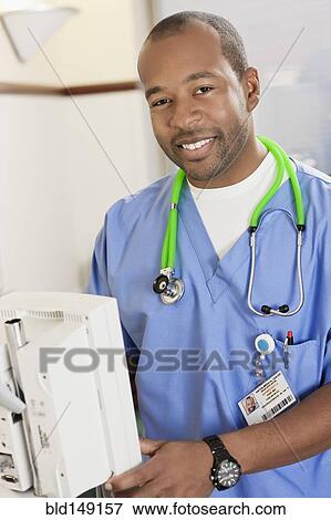 Stock Photo - Black doctor using equipment in hospital. Fotosearch