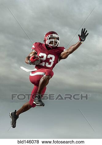 Black football player carrying football in mid-air View Large Photo Image Stock Photo - Black football player carrying football in mid-air. Fotosearch