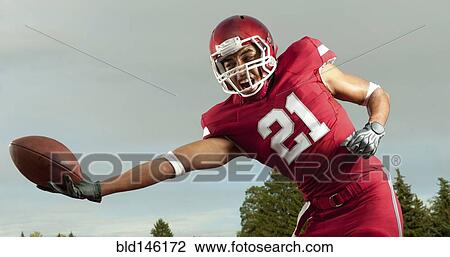 Stock Image - Black football player catching football. Fotosearch