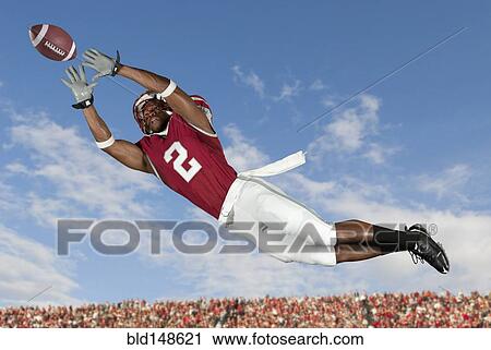 Stock Image - Black football player catching football in mid-air. Fotosearch