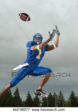 Stock Photo - Black football player catching football player in mid-air. Fotosearch
