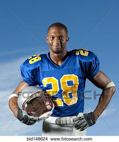 Picture - Black football player holding helmet. Fotosearch