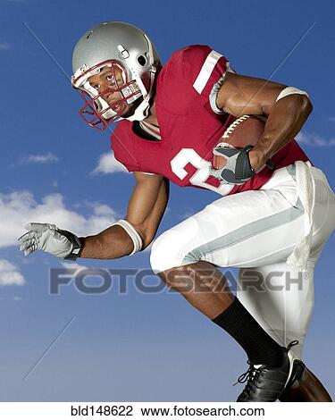 Stock Image - Black football player running with football. Fotosearch