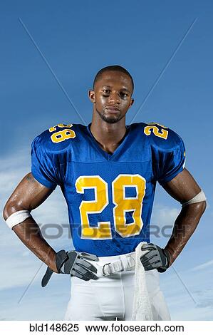 Stock Photography - Black football player standing with hands on hips. Fotosearch
