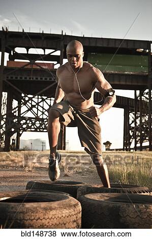 Black man running through tire obstacle course View Large Photo Image Stock Photo - Black man running through tire obstacle course. Fotosearch