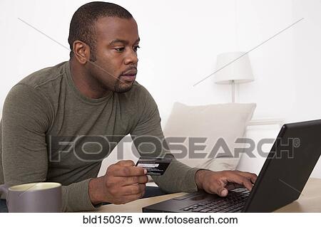 Stock Photography - Black man shopping online with credit card. Fotosearch