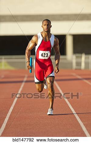 Stock Image - Black runner running on track in relay race. Fotosearch