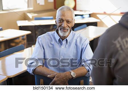 Black teacher sitting in classroom View Large Photo Image Picture - Black teacher sitting in classroom. Fotosearch