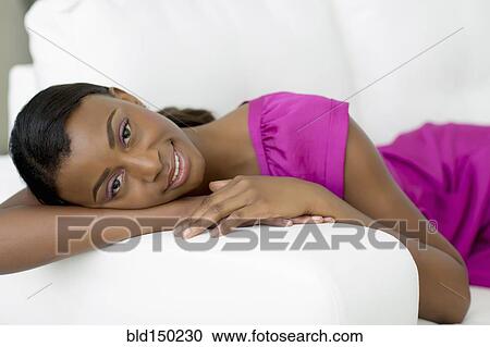 Stock Image - Black woman laying on sofa. Fotosearch