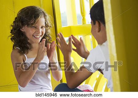 Stock Photograph - Brother and sister playing clapping game. Fotosearch