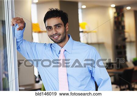 Stock Photo - Businessman leaning against wall in office. Fotosearch