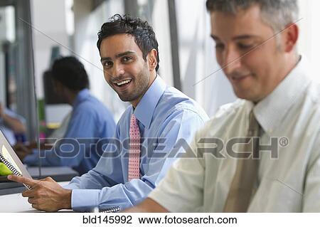Stock Image - Businessmen working in office. Fotosearch