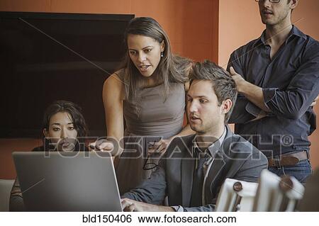 Stock Photograph - Businesspeople using laptop in meeting. Fotosearch