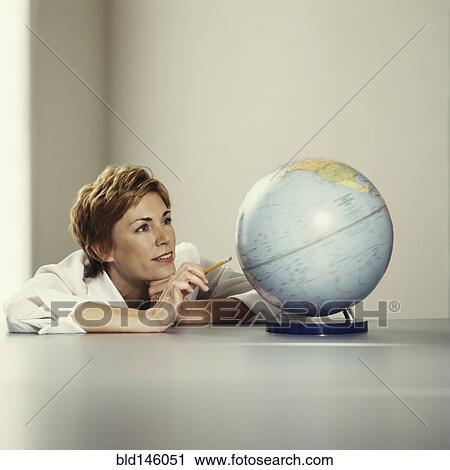 Stock Image - Businesswoman looking at globe. Fotosearch