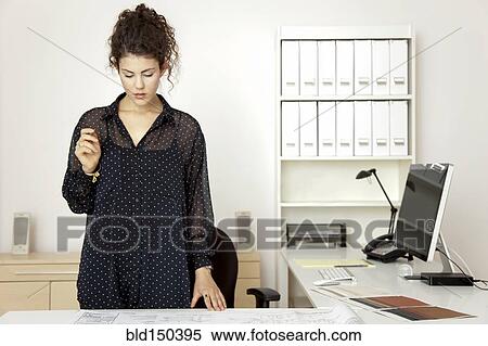 Stock Photography - Caucasian architect looking at blueprints. Fotosearch