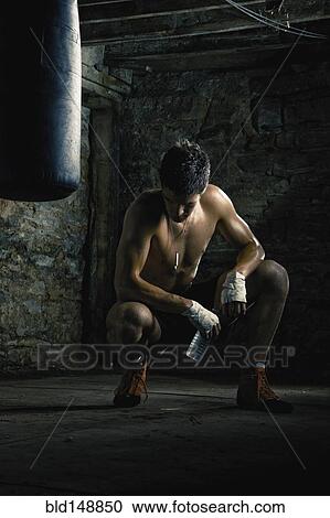 Stock Image - Caucasian boxer drinking water after training. Fotosearch