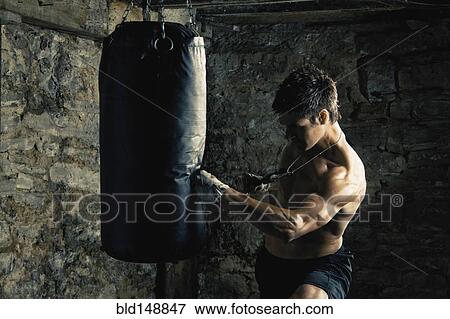 Stock Photo - Caucasian boxer training and hitting punching bag. Fotosearch