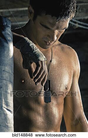 Stock Photo - Caucasian boxer with taped hands leaning on punching bag. Fotosearch