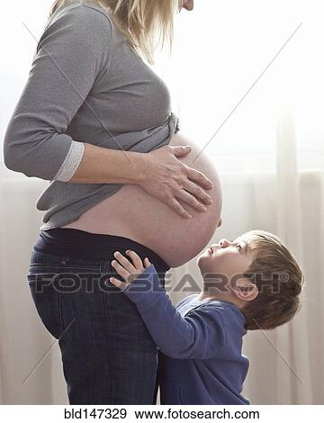 Stock Photo - Caucasian boy looking at pregnant woman's stomach. Fotosearch