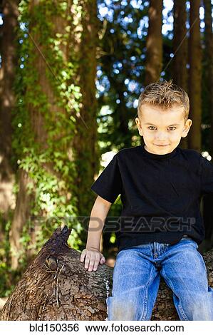 Caucasian boy sitting on log in forest View Large Photo Image Stock Photograph - Caucasian boy sitting on log in forest. Fotosearch