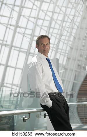 Caucasian businessman leaning on railing with hands in pockets View Large Photo Image Stock Image - Caucasian businessman leaning on railing with hands in pockets. Fotosearch