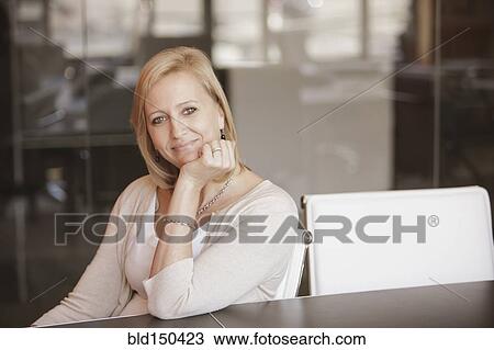 Stock Image - Caucasian businesswoman smiling at desk. Fotosearch