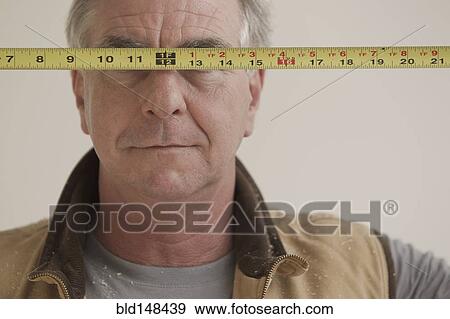 Caucasian carpenter covering eyes with measuring tape View Large Photo Image Stock Photo - Caucasian carpenter covering eyes with measuring tape. Fotosearch