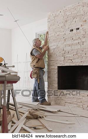 Picture - Caucasian carpenter measuring fireplace. Fotosearch
