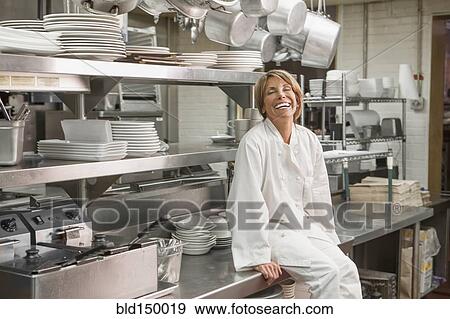 Stock Photo - Caucasian chef sitting in commercial kitchen. Fotosearch