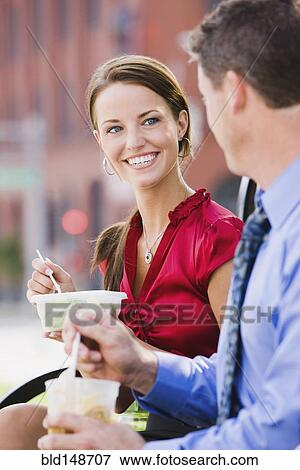 Stock Photo - Caucasian co-workers having lunch together outdoors. Fotosearch