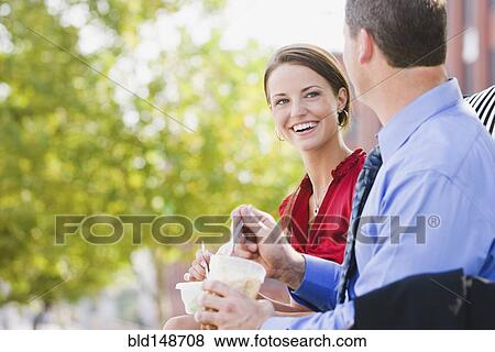 Stock Photo - Caucasian co-workers having lunch together outdoors. Fotosearch