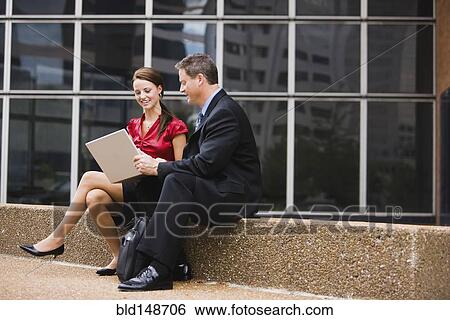 Caucasian co-workers using laptop together outdoors View Large Photo Image Stock Photograph - Caucasian co-workers using laptop together outdoors. Fotosearch