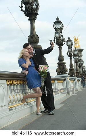 Caucasian couple taking self-portrait on bridge View Large Photo Image Stock Photograph - Caucasian couple taking self-portrait on bridge. Fotosearch