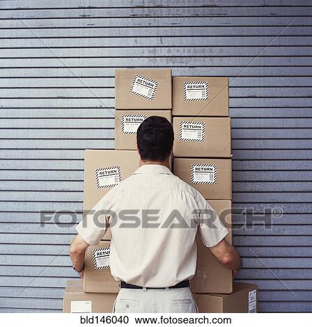 Stock Image - Caucasian delivery man delivering boxes. Fotosearch