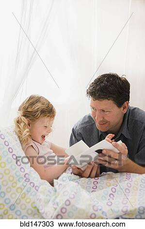 Caucasian father reading book to daughter in bed View Large Photo Image Stock Image - Caucasian father reading book to daughter in bed. Fotosearch