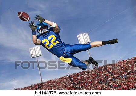 Stock Photo - Caucasian football player catching ball. Fotosearch