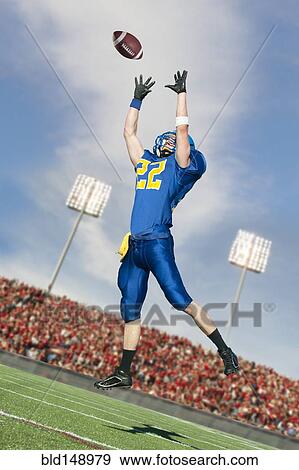 Stock Photo - Caucasian football player catching ball. Fotosearch