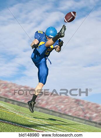 Stock Image - Caucasian football player kicking ball. Fotosearch