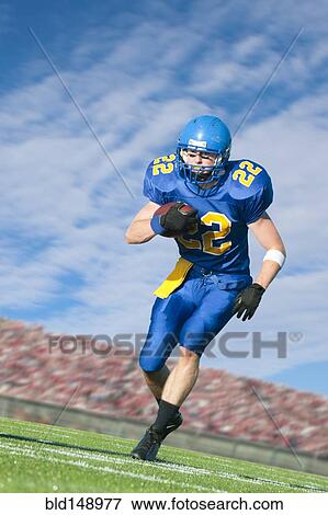 Stock Photo - Caucasian football player running with ball. Fotosearch