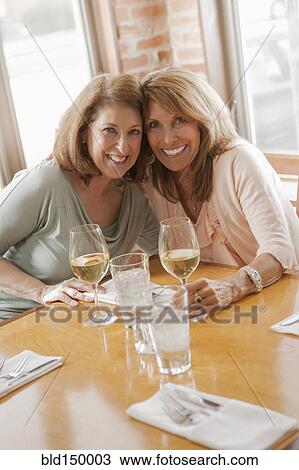 Stock Image - Caucasian friends drinking wine in restaurant. Fotosearch