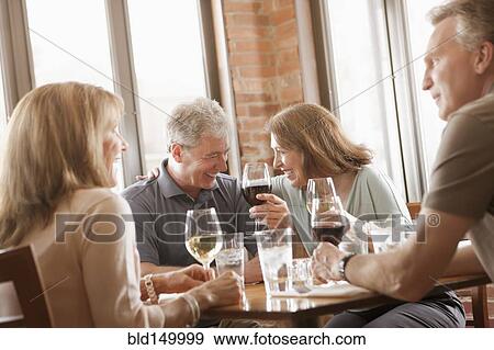 Stock Photo - Caucasian friends drinking wine in restaurant. Fotosearch