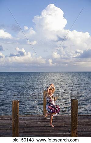 Stock Photo - Caucasian girl dancing on pier. Fotosearch