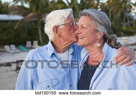 Stock Photography - Caucasian man kissing wife on beach. Fotosearch