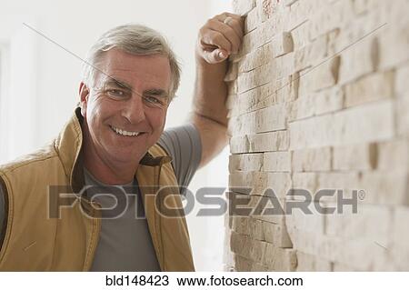 Stock Image - Caucasian man leaning against wall. Fotosearch