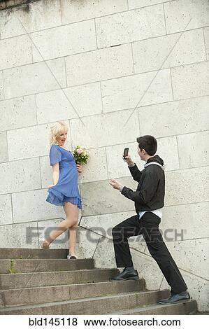 Stock Photo - Caucasian man photographing girlfriend. Fotosearch