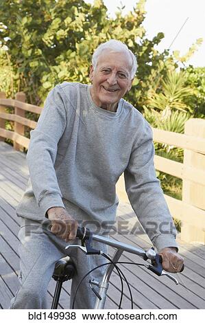 Stock Photo - Caucasian man riding bicycle on bridge. Fotosearch