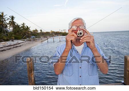 Caucasian man taking photographs on beach View Large Photo Image Picture - Caucasian man taking photographs on beach. Fotosearch