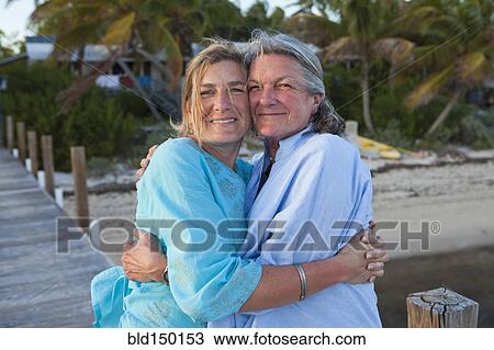 Stock Image - Caucasian mother and daughter hugging on pier. Fotosearch